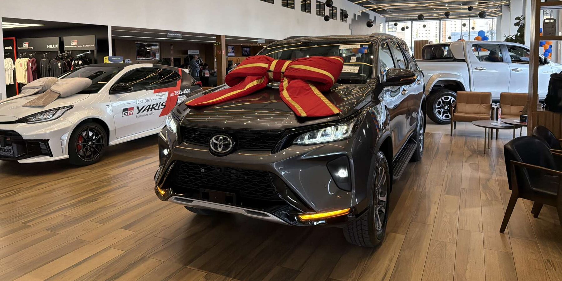 Toyota SW4 Diamond 0km cinza com laço vermelho no capô - foto da campanha